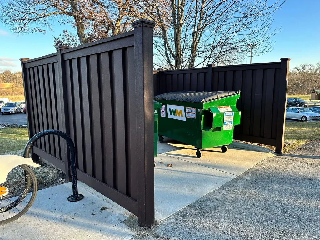 Commercial bins in an enclosure on a concrete dumpster pad